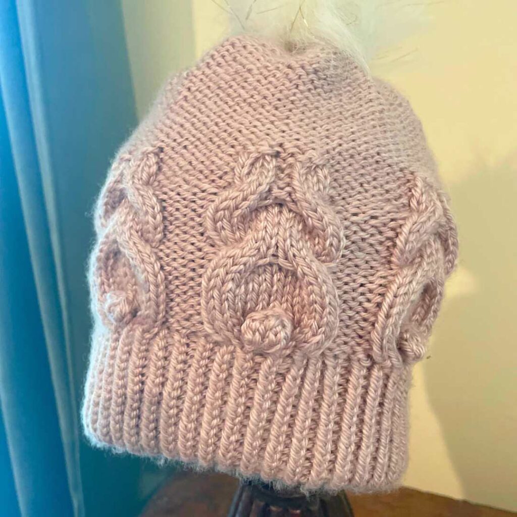 Get information on the knitting pattern for Nora's hat with bunny cables.